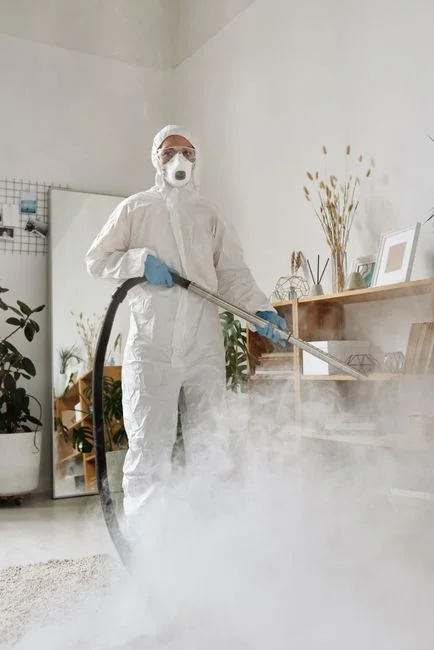 brand-01 A person in full PPE gear standing indoors, emphasizing disinfection during COVID-19.